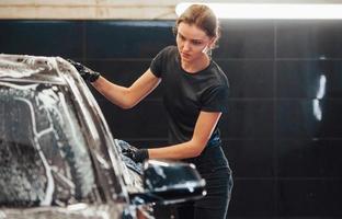 doekjes voertuig dat is in wit zeep. modern zwart auto- krijgen schoongemaakt door vrouw binnen van auto wassen station foto