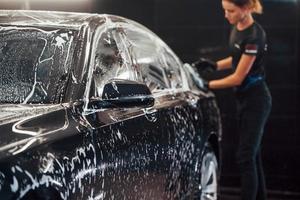 doekjes voertuig dat is in wit zeep. modern zwart auto- krijgen schoongemaakt door vrouw binnen van auto wassen station foto