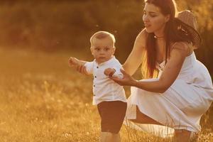 gelukkig moeder met haar zoon uitgeven vrij tijd Aan de veld- Bij zonnig dag tijd van zomer foto