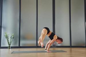 moeilijk oefening. jong vrouw in sportief slijtage en met slank lichaam hebben geschiktheid yoga dag binnenshuis foto