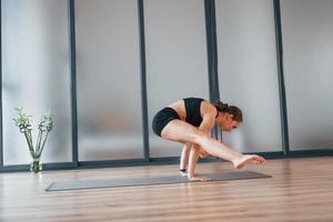 moeilijk oefening. jong vrouw in sportief slijtage en met slank lichaam hebben geschiktheid yoga dag binnenshuis foto
