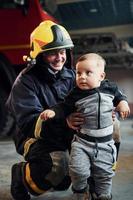 schattig weinig jongen is met mannetje brandweerman in beschermend uniform foto