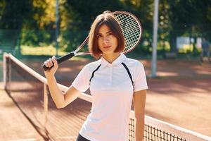 staand met racket in hand. vrouw tennis speler is Aan de rechtbank Bij dag foto