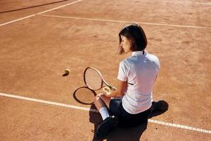 achterzijde visie. vrouw tennis speler is Aan de rechtbank Bij dag foto