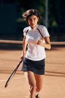 rennen naar voren. vrouw tennis speler is Aan de rechtbank Bij dag foto