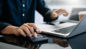 dichtbij omhoog van zakenvrouw of accountant hand- typen laptop werken naar berekenen Aan bureau over kosten Bij huis kantoor. foto