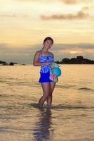 meisje Aan de strand Bij zonsopkomst over- de zee foto