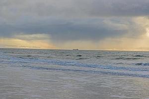 afbeelding van vervoer schip Aan stormachtig zee gefotografeerd van een strand foto