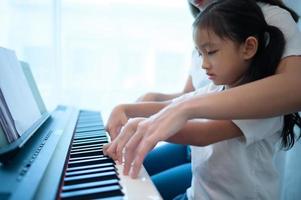 familie vakantie, andere helpen dochter praktijk in haar piano lessen foto