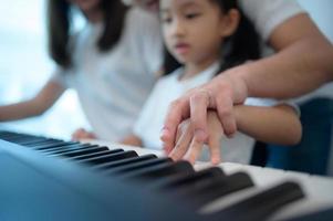 familie vakantie, vader en moeder helpen dochter praktijk in haar piano lessen foto