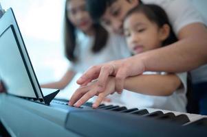 familie vakantie, vader en moeder helpen dochter praktijk in haar piano lessen foto
