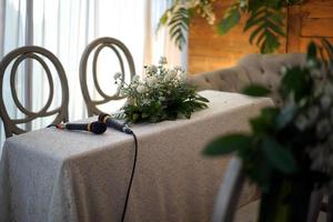 twee microfoons en bloemen Aan een tafel voor bruiloft processie foto