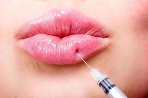 detailopname schot van mooi jong vrouw ontvangen vulmiddel injectie in lippen, schoonheid behandeling concept foto