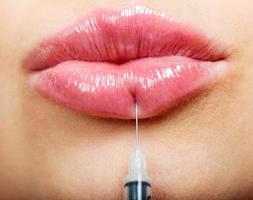 detailopname schot van mooi vrouw lippen en injectiespuit met vulmiddel foto