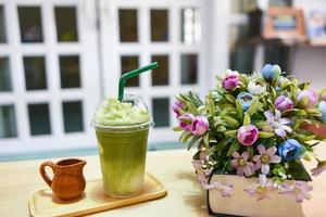 groen thee smoothie - matcha groen thee met melk Aan plastic glas Aan de tafel in een cafe foto