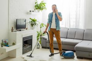 coronavirus pandemie. een Mens met een vacuüm schoonmaakster in zijn appartement. huis kantoor. quarantaine. afgelegen werk. een Mens in een bedrijf overhemd en onderbroek houdt. foto