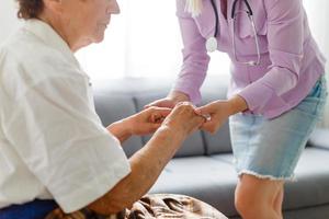 jong dokter Holding hand- van ouderen vrouw Aan licht achtergrond foto