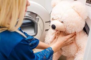 vrouw bezig met laden pluizig speelgoed- in de het wassen machine foto