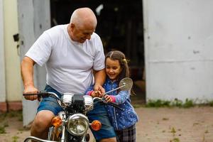 gelukkig opa en zijn kleindochter in de buurt fiets glimlachen foto