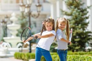 twee weinig meisjes met tennis rackets foto