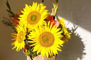 pot gedekt in jute en kant gevulde met faux zonnebloemen foto