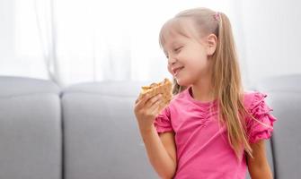 weinig meisje aan het eten pizza Bij huis foto