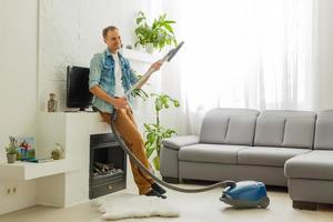 coronavirus pandemie. een Mens met een vacuüm schoonmaakster in zijn appartement. huis kantoor. quarantaine. afgelegen werk. een Mens in een bedrijf overhemd en onderbroek houdt. foto