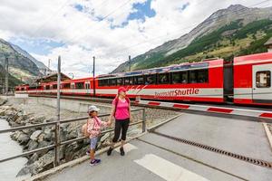 wandelaars met rugzak op zoek Bij bergen, alpine visie, moeder met kind foto