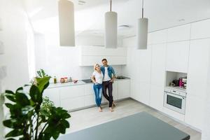 lief mooi paar staand en knuffelen Aan een keuken Bij huis foto