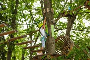 aanbiddelijk weinig meisje genieten van haar tijd in beklimming avontuur park Aan warm en zonnig zomer dag. zomer activiteiten voor jong kinderen. kind hebben pret Aan school- vakanties. foto