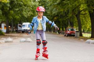 grappig weinig mooi meisje Aan rol skates in helm rijden in een park. gezond levensstijl concept. foto