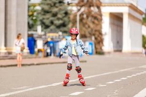 grappig weinig mooi meisje Aan rol skates in helm rijden in een park. gezond levensstijl concept. foto