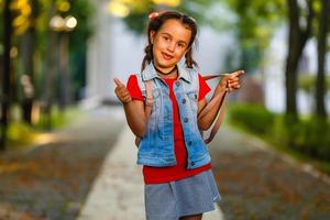 portret van aantrekkelijk Kaukasisch weinig leerling meisje met mooi bruin ogen. gelukkig glimlachen kind op zoek Bij camera - detailopname, buitenshuis. foto