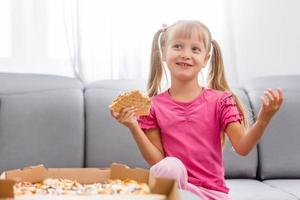 weinig meisje aan het eten pizza Bij huis foto