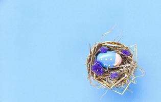 Pasen eieren in mand nest decoratie met Purper statice bloemen Aan blauw achtergrond foto