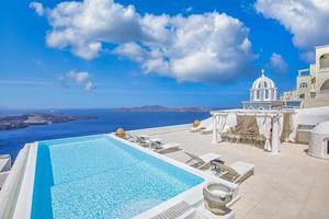 05.08.19, Santorini eiland, Griekenland - mooi vakantie concept sjees lounges Aan de terras en verbazingwekkend oneindigheid zwembad met zee visie. luxe reizen en toerisme bestemming, idyllisch wit strand luifel foto