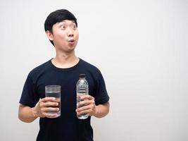 Aziatisch Mens Holding glas met water fles voelt opgewonden op zoek Bij kopiëren ruimte foto