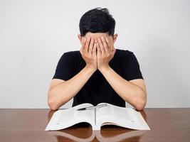 Aziatisch Mens houden zijn hoofd voelt hoofdpijn met lezing boek Aan de tafel foto