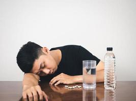 slapeloos Mens houdende Bij tafel met geneeskunde pil en water voelt ziek foto