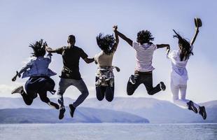 portret van jong vrienden jumping van steiger in meer. vrienden in midden lucht Aan een zonnig dag Bij de meer. foto
