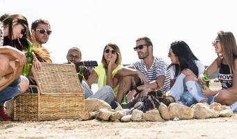 zomer, vakantie, vakantie, muziek, gelukkig mensen concept - groep van vrienden met gitaar hebben pret Aan de strand foto