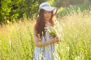 jong vrouw plukken bloemen in de weide in zomer avond foto