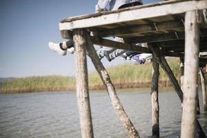 paar van vrienden ontspannende Aan de Peer door een meer. zomer vakantie concept foto