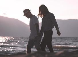 gelukkig romantisch paar genieten van mooi zonsondergang wandelen Aan de strand. reizen vakantie pensioen levensstijl concept foto