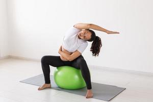 mooi jong zwanger vrouw aan het doen oefening Bij huis Aan fitball foto