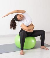 jong flexibel zwanger vrouw aan het doen gymnastiek Aan tapijt Aan de verdieping Aan wit achtergrond. de concept van voorbereidingen treffen de lichaam voor gemakkelijk bevalling foto