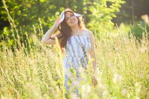 jong vrouw wandelen tussen wilde bloemen Aan zonnig zomer dag. concept van de vreugde van communiceren met zomer natuur foto