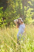 jong vrouw wandelen tussen wilde bloemen Aan zonnig zomer dag. concept van de vreugde van communiceren met zomer natuur foto