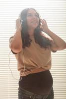 zwanger vrouw luister naar muziek- in hoofdtelefoons Bij huis en dansen foto