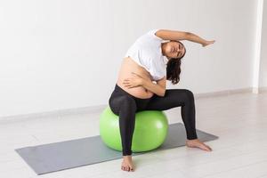 jong flexibel zwanger vrouw aan het doen gymnastiek met geschiktheid bal. de concept van voorbereidingen treffen de lichaam voor gemakkelijk bevalling foto